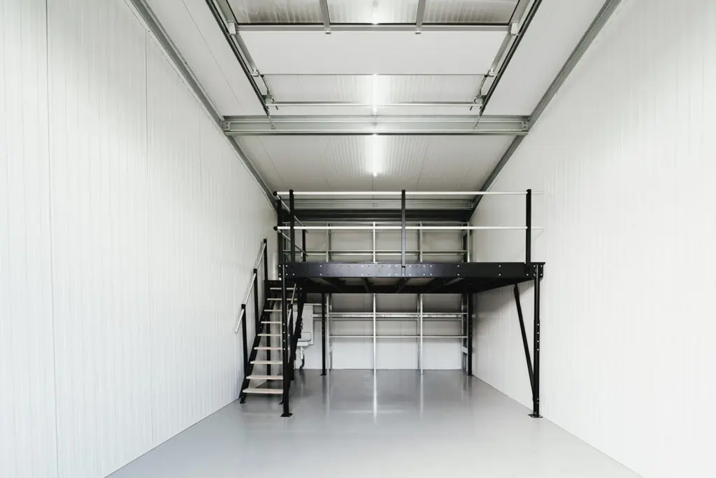 Hohe Lagerhalle mit Metalltreppe und großer Zwischenebene bei Lager4all
