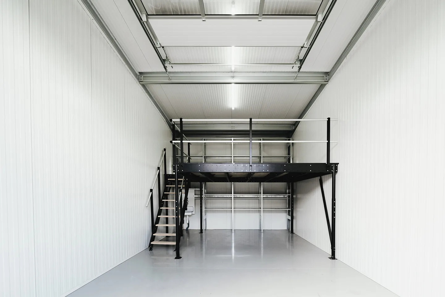 Hohe Lagerhalle mit Metalltreppe und großer Zwischenebene bei Lager4all