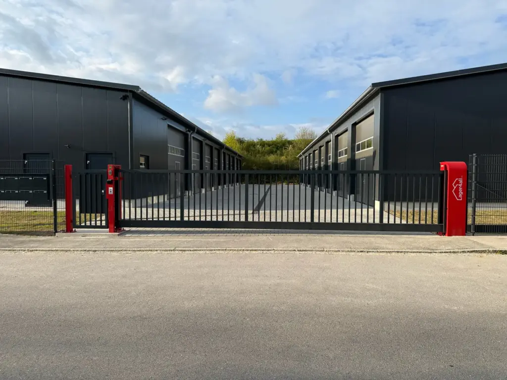 Großes geschlossenes Schiebetor vor zwei Reihen moderner Lagerhallen in Mering