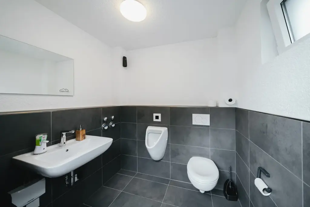 Sauberer Sanitärbereich mit Waschbecken, WC und Urinal bei Lager4all